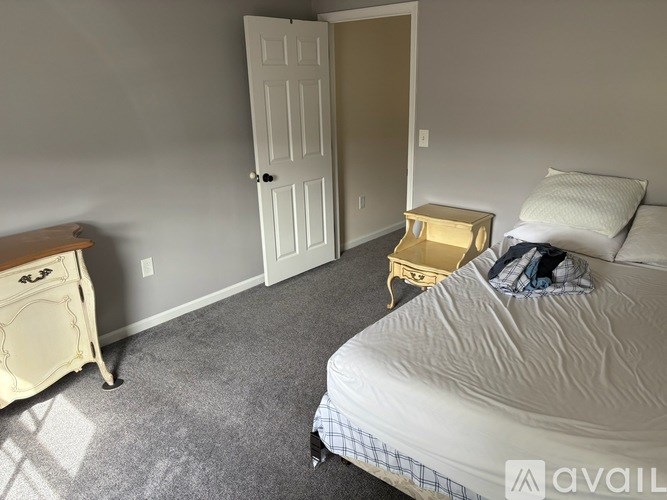 A bedroom with a bed, nightstand, and chair.