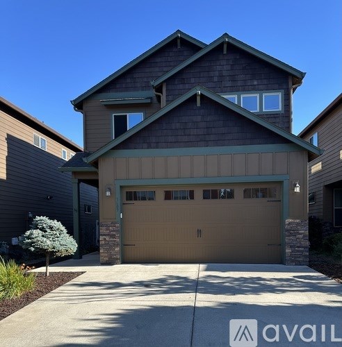 A modern house with a large garage door and a stone pillar.