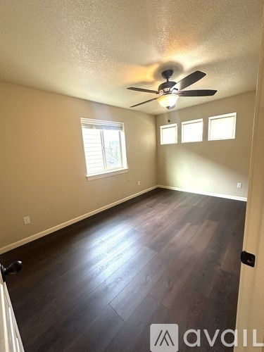 A room with a ceiling fan and wooden flooring.