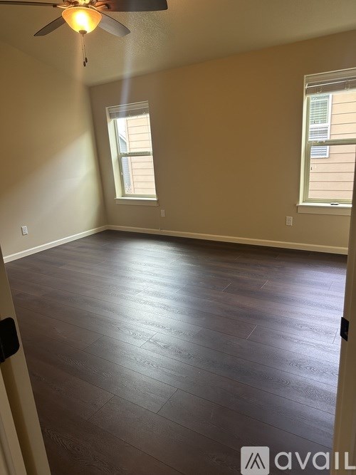 A room with a ceiling fan and two windows.