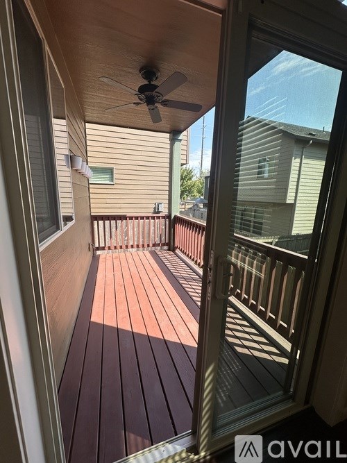 A balcony with a ceiling fan and a view of a house across the way.