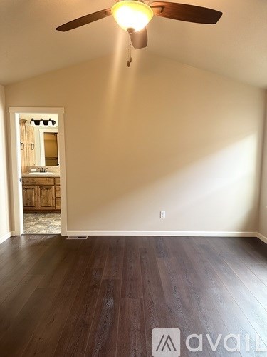 A room with a ceiling fan and wooden flooring.