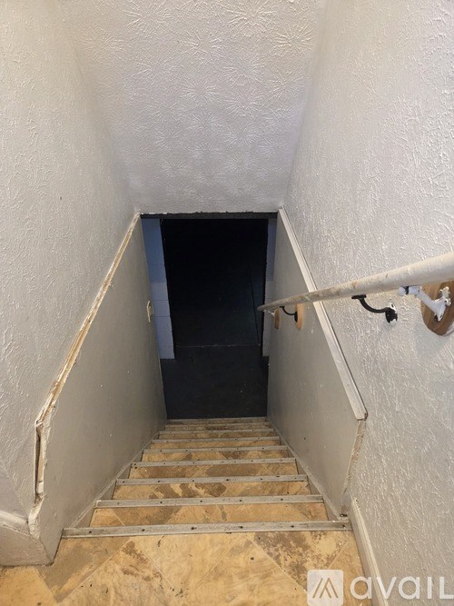 A stairway with a black door at the bottom.
