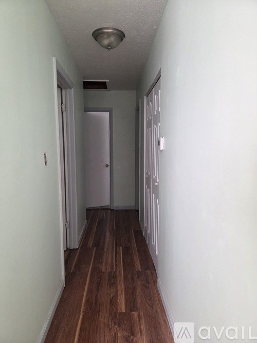 A long hallway with wood floors and white walls.