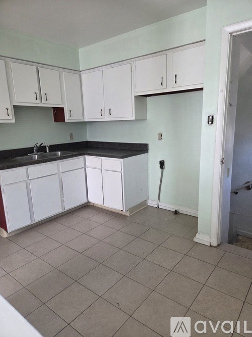 A kitchen with white cabinets and a black countertop.