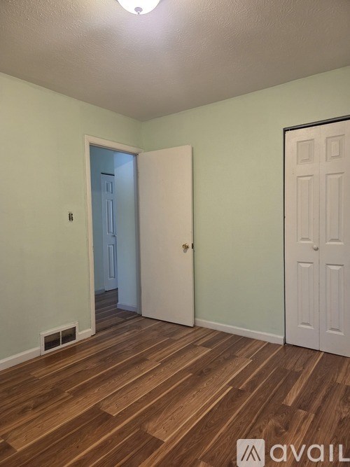 A room with a wooden floor and two doors, one of which is open.