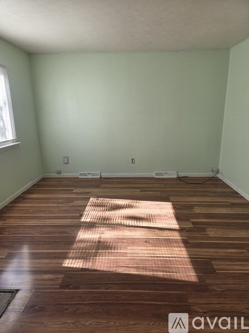 A room with wooden floors and a window letting in sunlight.