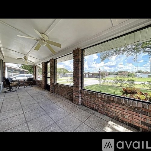 A patio with a ceiling fan and a brick wall.