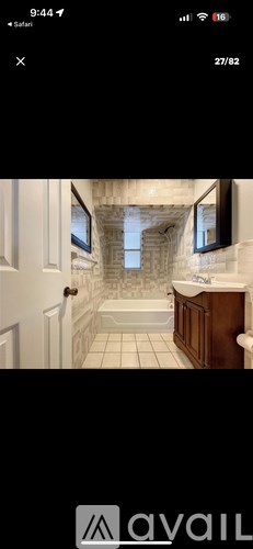 A bathroom with a white tiled floor and a stone wall.