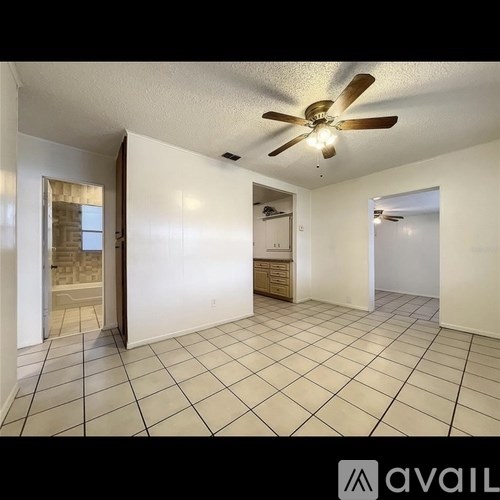 A spacious room with a ceiling fan and tiled flooring.