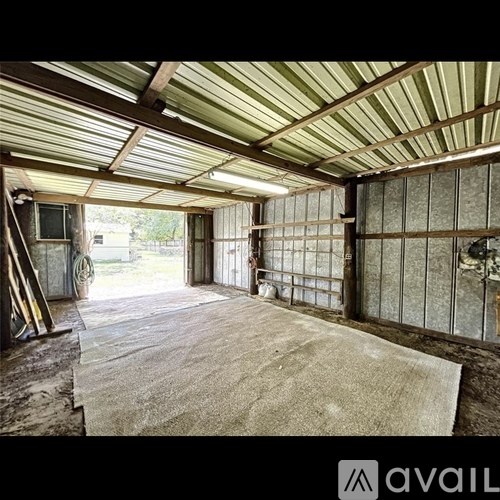 A large, empty room with a high ceiling and a doorway leading outside.