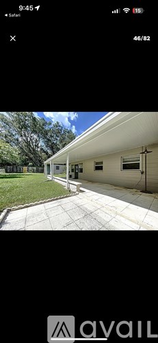 A white building with a porch and a tree in the background.