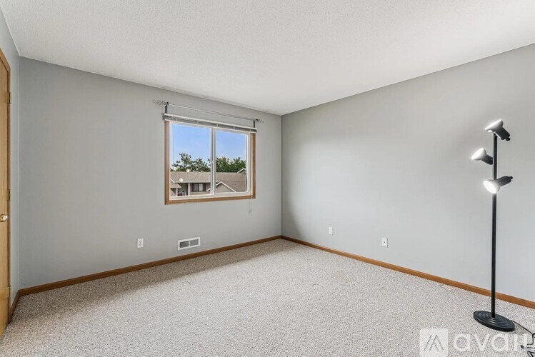 A room with a window and a lamp on the floor.