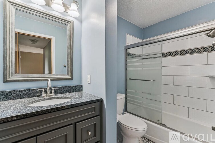A bathroom with a sink, mirror, toilet and shower.