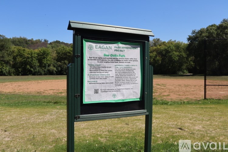 A green signboard with information about Bur Oaks Park stands in a field.