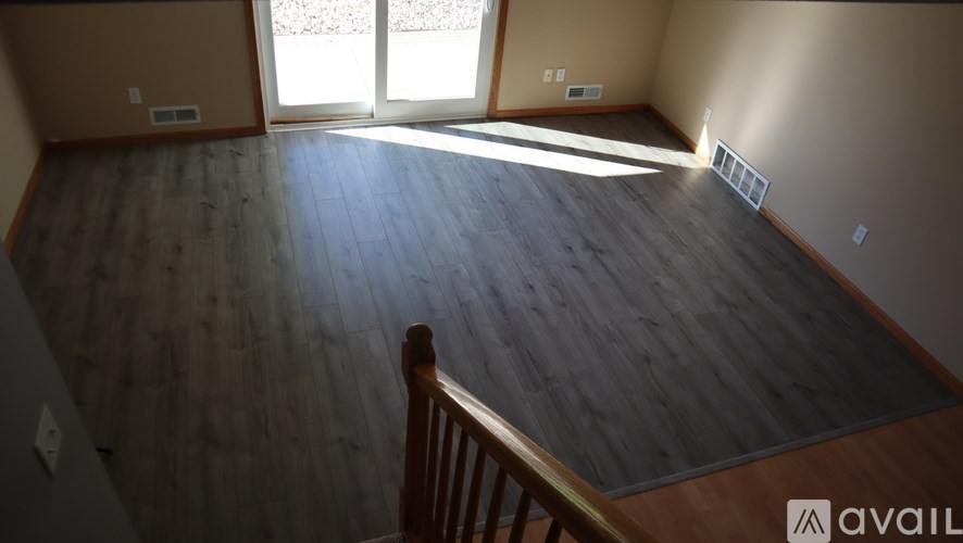 A room with wooden flooring and a staircase leading to another room.
