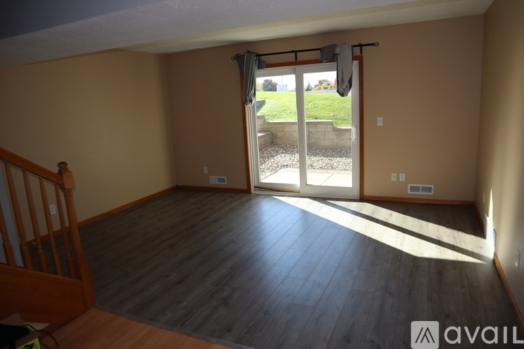 A room with wooden floors and a sliding glass door leading to a backyard.