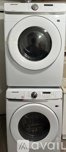A stack of white washing machines with the front loading machine on top.