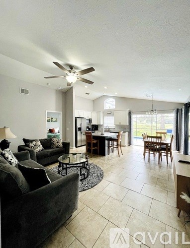 A living room with a grey couch and a ceiling fan.