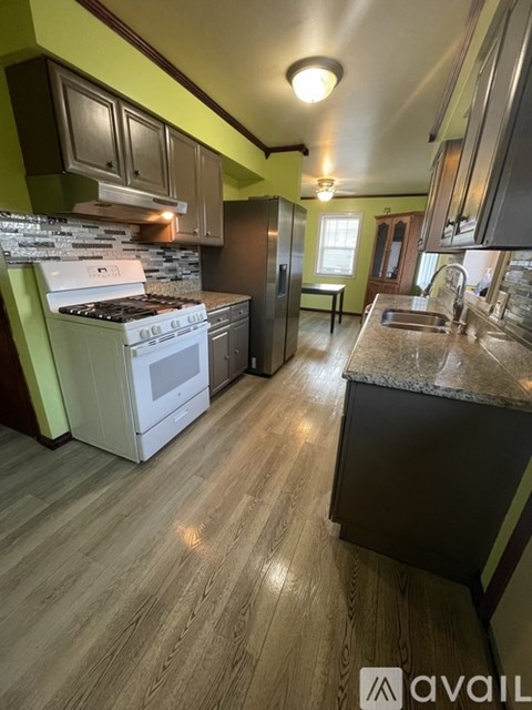 A kitchen with a white stove and wooden floors.