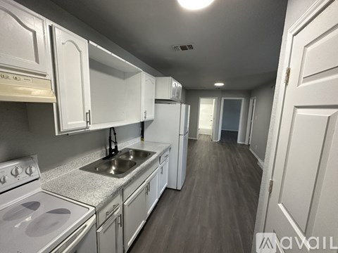 A kitchen with white cabinets and a stove top oven.
