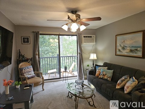 A living room with a couch, chairs, and a ceiling fan.