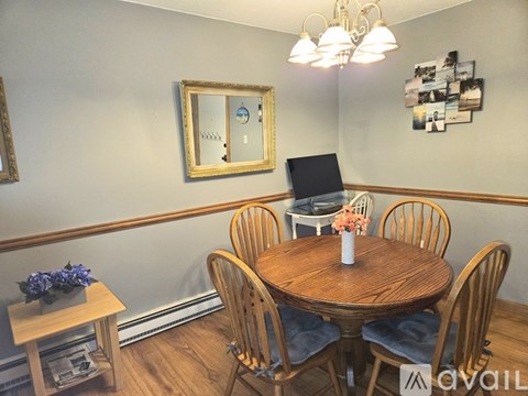 A dining room with a round wooden table surrounded by chairs.