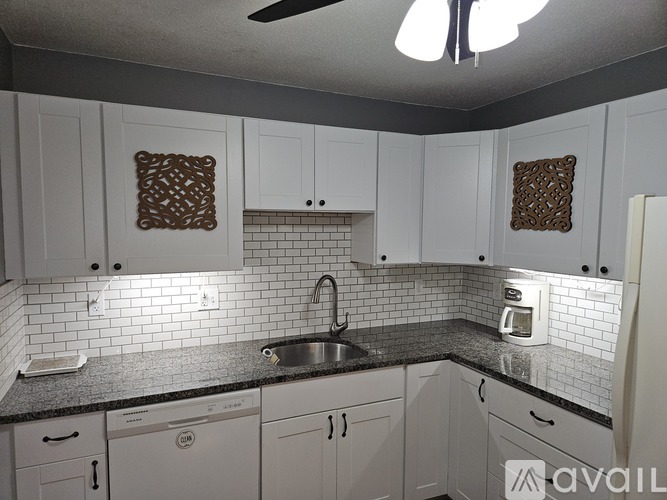 A kitchen with white cabinets and a black countertop.