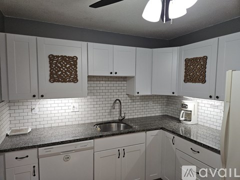 A kitchen with white cabinets and a black countertop.