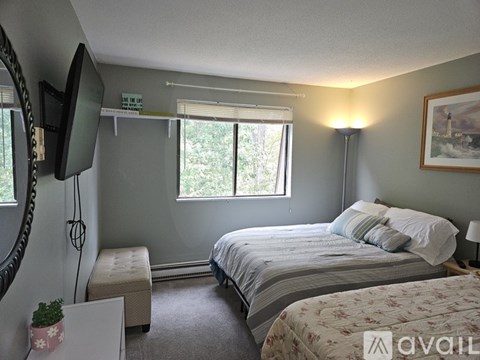 A bedroom with a bed, a bench, and a television.