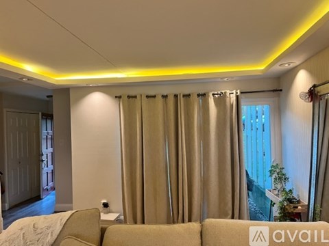 A living room with a couch and a window with curtains.