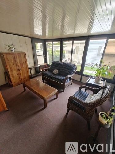 A living room with a wicker chair and a wooden table.