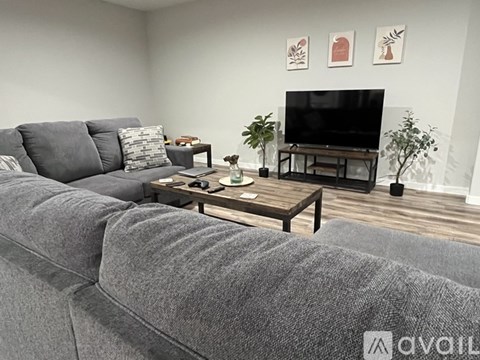 A grey couch sits in a living room with a television and a coffee table.