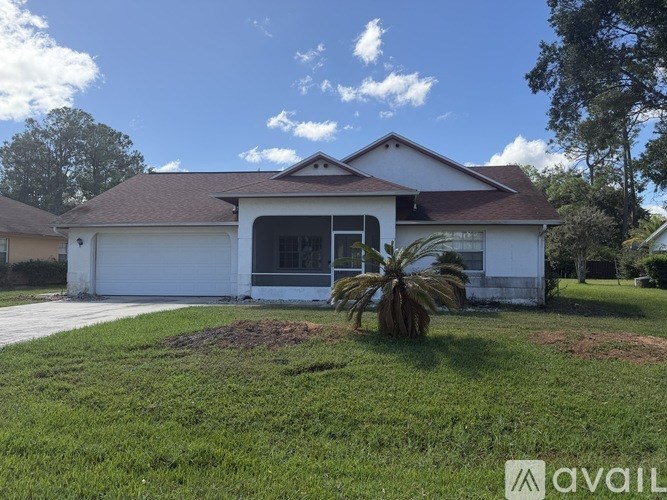 A white house with a brown roof and a palm tree in front.
