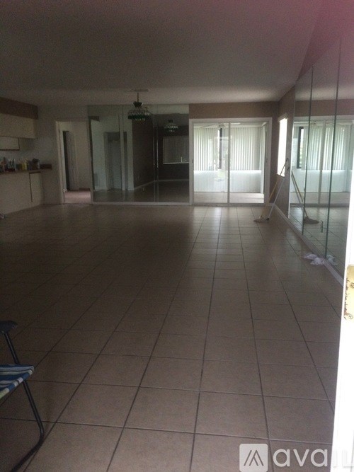 A spacious room with tiled flooring and a glass door leading to another room.