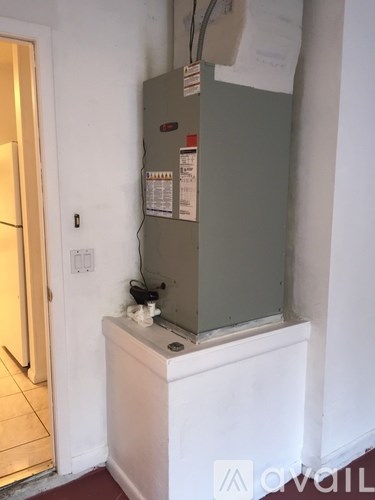 A cat is sitting on a white baseboard next to a grey wall.
