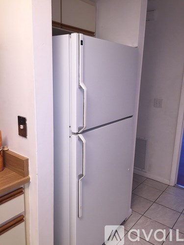 A white refrigerator in a kitchen with a wooden drawer.