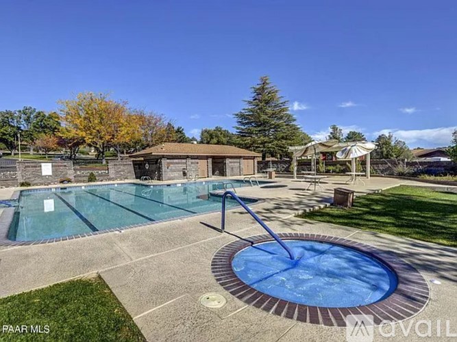 A swimming pool with a hot tub and a pavilion in the background.
