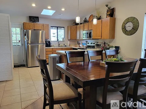 A kitchen with a table and chairs in the foreground and a refrigerator in the background.