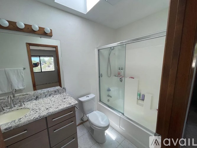 A bathroom with a toilet, sink, mirror, and shower.