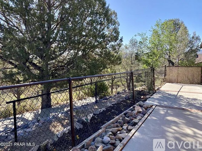 A fenced pathway with rocks on the side and trees in the background.