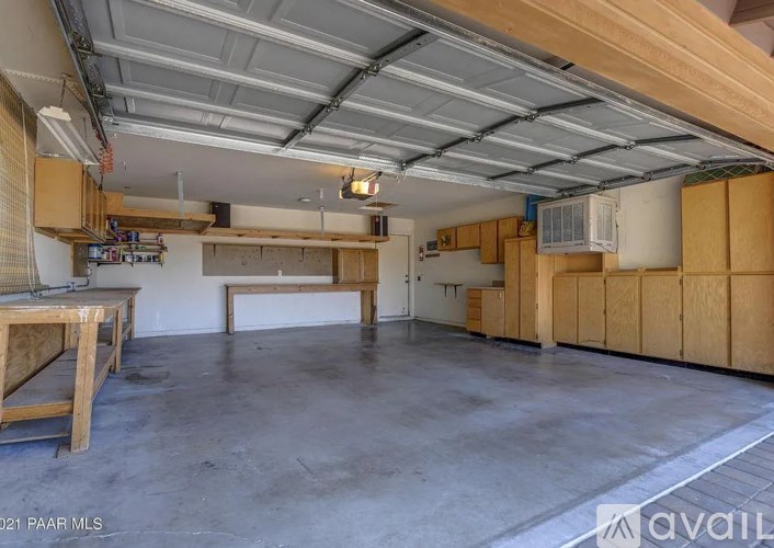 A spacious garage with a concrete floor and a ceiling covered in ductwork.