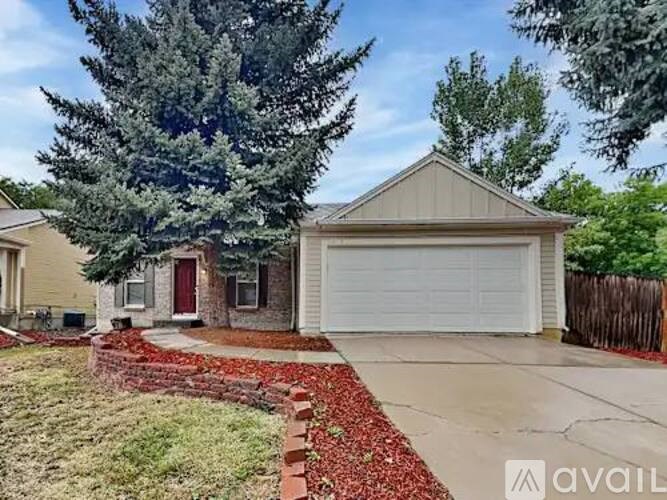 A house with a garage and a tree in front.