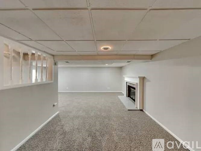 A spacious room with a fireplace and carpeted floor.