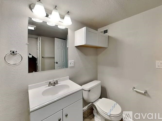 A small bathroom with a toilet, sink, and mirror.