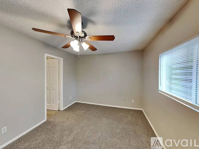 A room with a ceiling fan and a window with blinds.