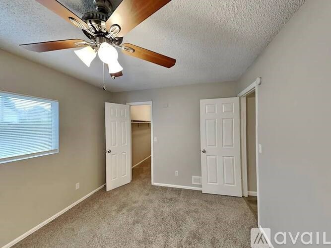 A room with a ceiling fan and two doors.