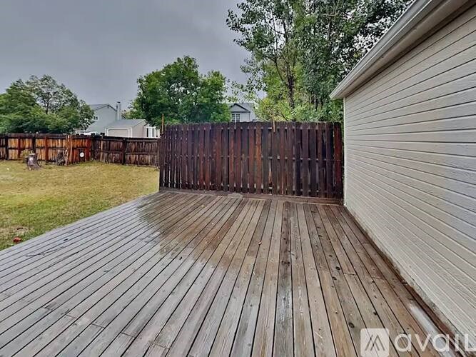 A wooden deck leads to a wooden fence.
