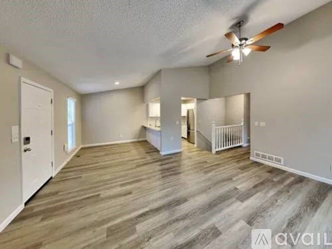 A spacious room with wood flooring and a ceiling fan.