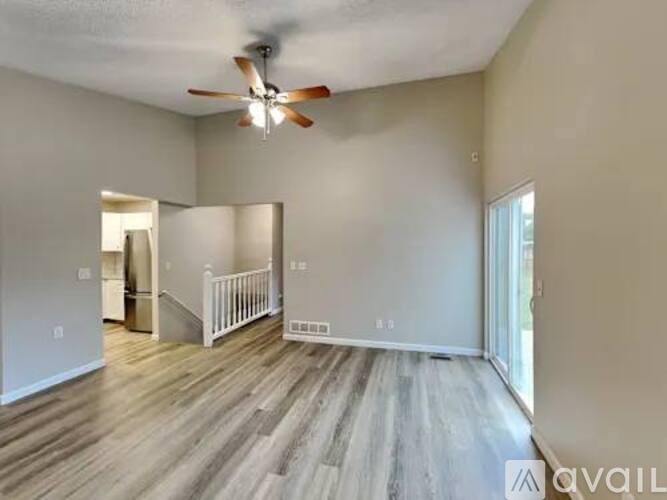 A spacious room with a ceiling fan and wooden flooring.